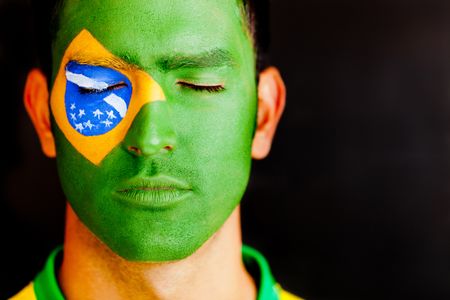 Patriotic man from Brazil with flag painted on his face and eyes closed