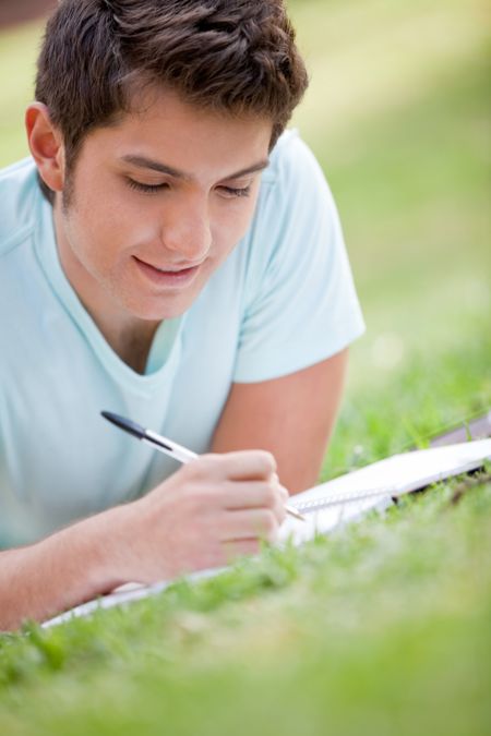 Casual man studying outdoors with a notebook
