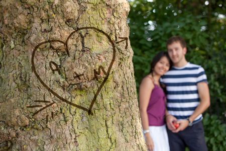 Happy couple in love with their initials carved in a tree