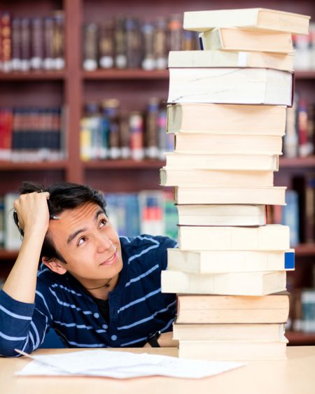 Overwhelmed male student with a pile of books