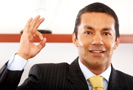 business man smiling doing the ok sign in his office