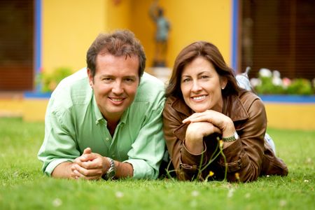 happy couple portrait outdoors lying on the floor outside their home