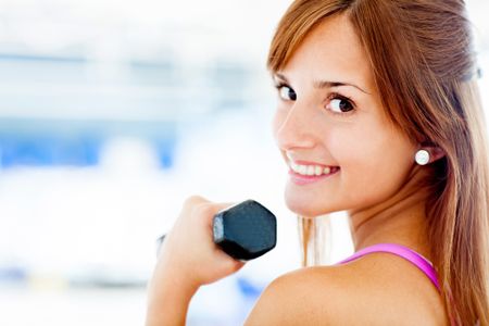 Woman lifting weights at the gym looking happy