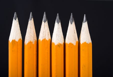 black pencils in a row over a black background