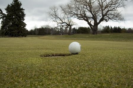 Muddy practice ball by hole on golf course