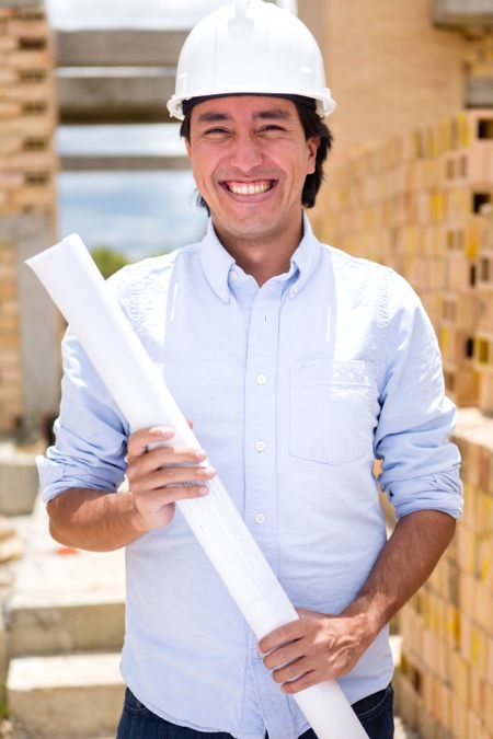 Architect at a construction site holding blueprints