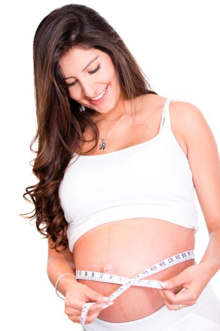 Woman measuring her pregnant belly - isolated over a white background