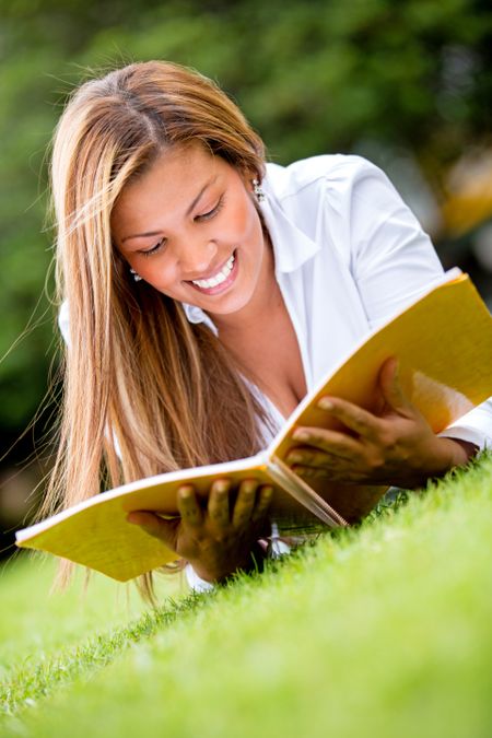 Beautiful woman reading outdoors looking very happy