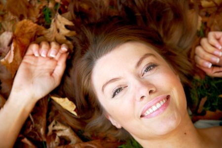 beautiful autumn woman smiling on the floor surrounded by leaves