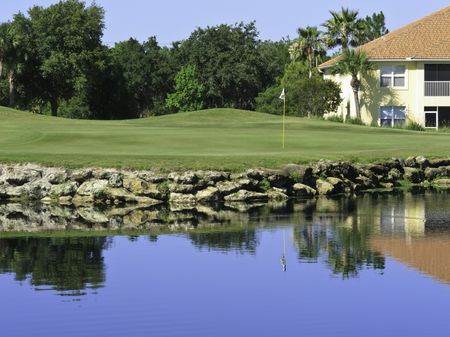 Putting green by pond and house on golf course in Florida
