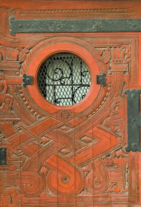 Ornate exterior wooden door with porthole-sized peephole in historic neighborhood