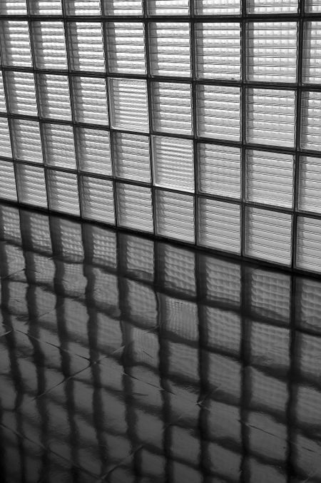 Wall of opaque window panes and reflections on linoleum floor