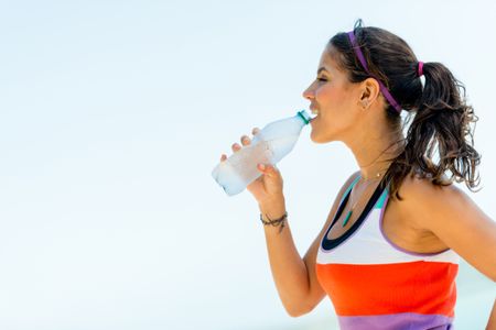 Fit woman drinking water from a bottle outdoors