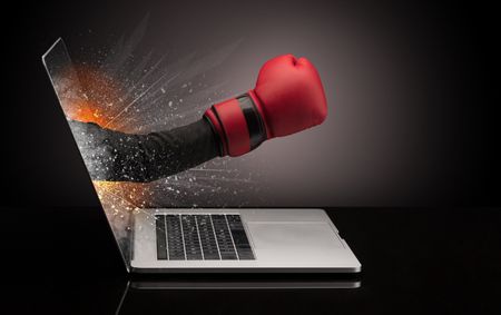 Hand with boxing gloves coming out of a laptop with sparkling effects