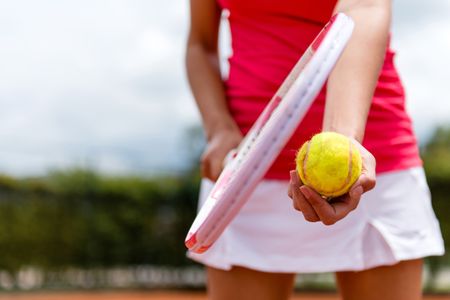 Female tennis player holding racket and a ball