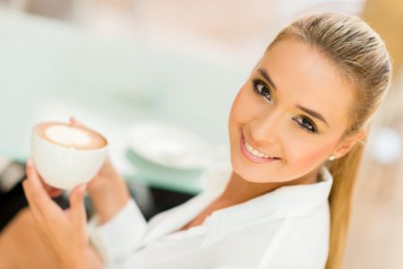Beautiful woman drinking a cup of coffee and smiling