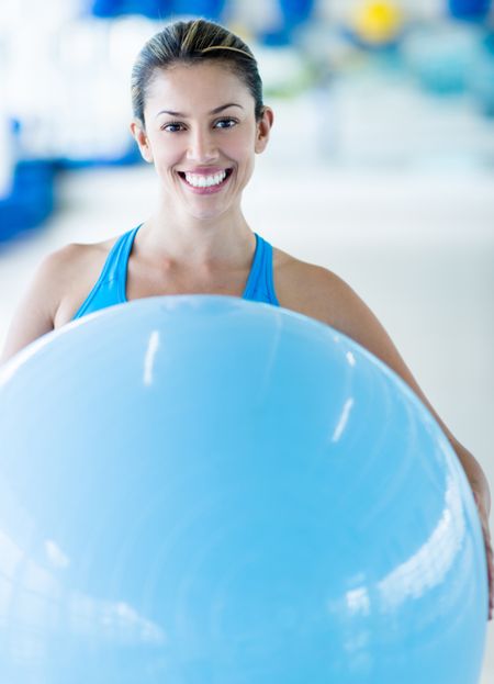 Happy woman at the gym holding a Pilates ball
