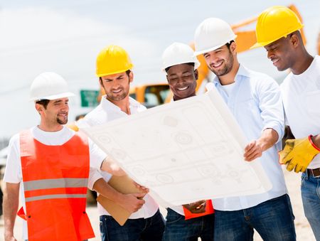 Group of workers at a construction site looking at blueprints 