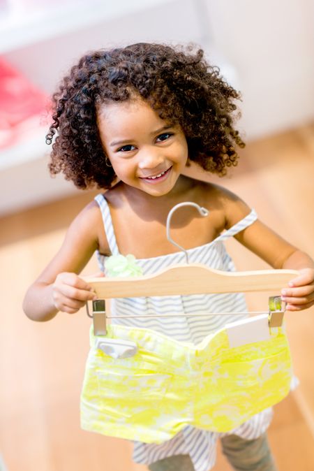 Cute little girl shopping for clothes and smiling 