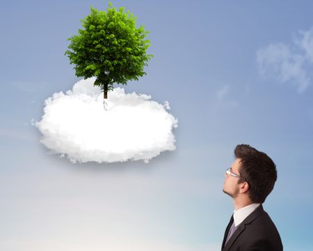 Young man pointing at a green tree on top of a white cloud concept