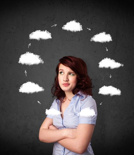 Thoughtful young woman with drawn clouds circulating around her head