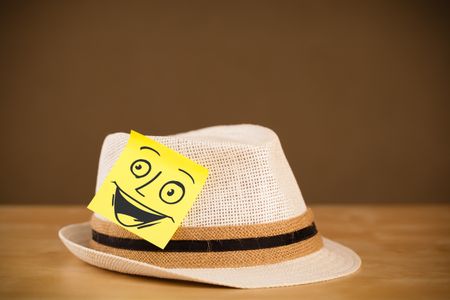 Drawn smiley face on a post-it note sticked on a hat