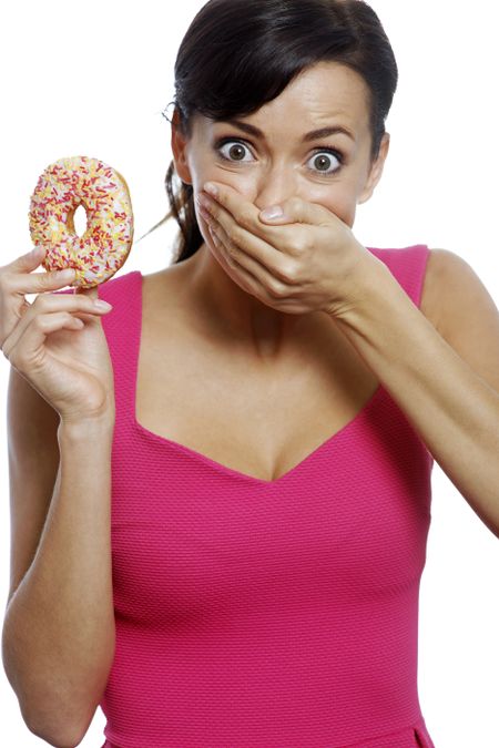 Young woman holding a doughnut looking guilty