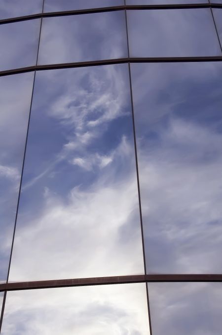 Reflection of morning clouds in glass wall on college campus