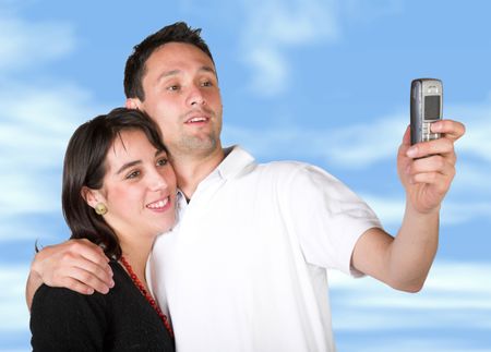 couple taking a pic with cell phone with sky in the background - clipping path included to replace the background easily