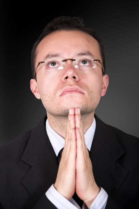 business man praying over a dark background