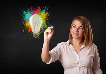 Young lady drawing a colorful light bulb with colorful splashes on white background