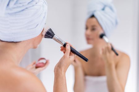 middle aged woman applying makeup