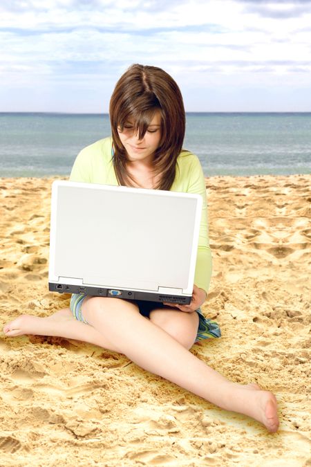 casual girl using a laptop on the beach on a sunny day