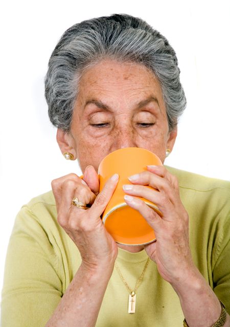 elderly woman drinking a hot drink over white