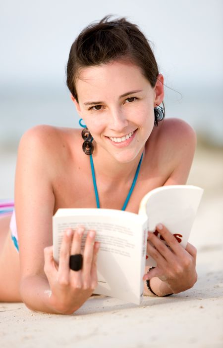 beach woman reading a book lying on the sand