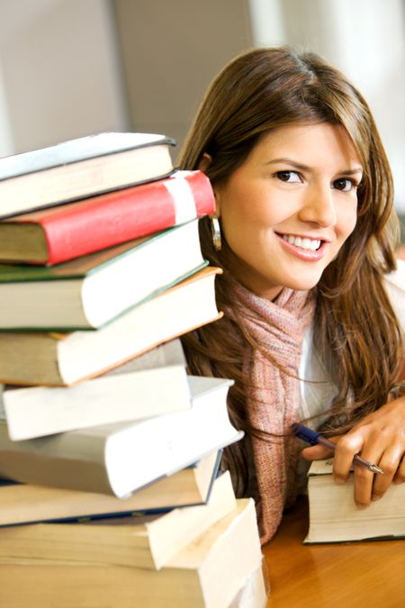 beautiful female student looking happy and smiling with a book in the library