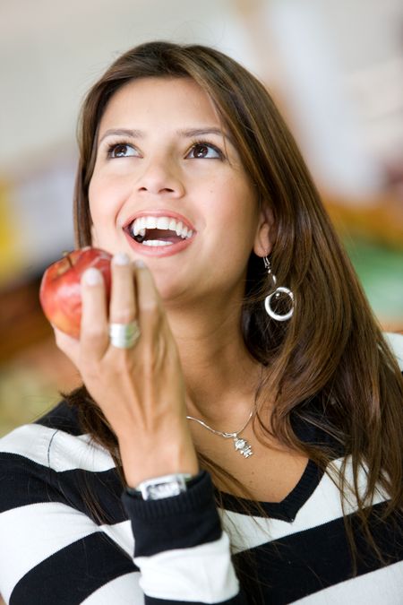 casual woman with an apple in a supermarket smiling