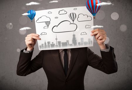 Businessman holding a cardboard in front of his head with cityscape and ballons drawing