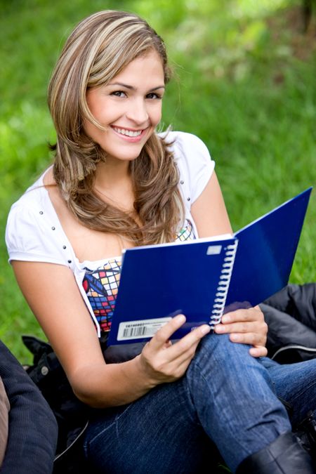 female university student smiling with a notebook outdoors