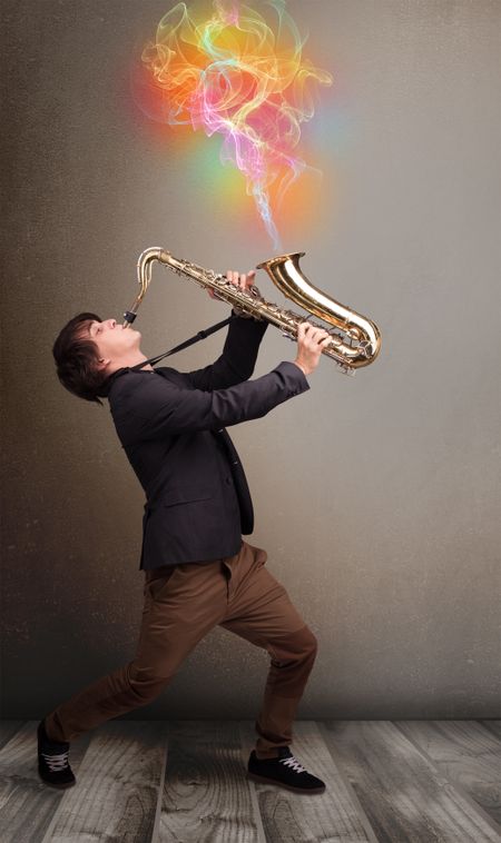 Attractive young musician playing on saxophone with colorful abstract fume comming out