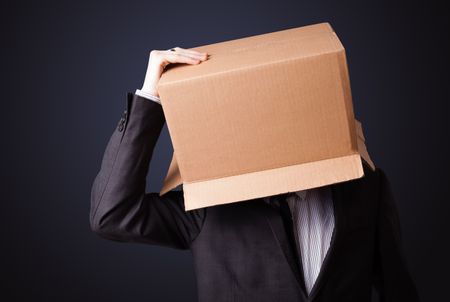 Businessman standing and gesturing with a cardboard box on his head