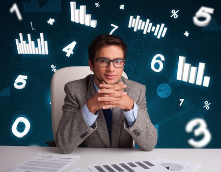 Young businessman sitting at desk with diagrams and statistics