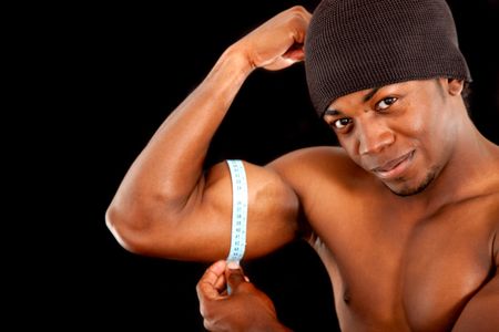 strong man measuring his bicep muscle isolated over a black background