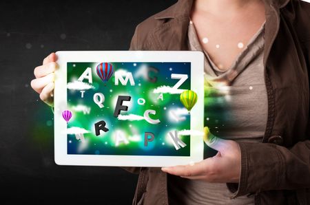 Young person showing white tablet with abstract letters and sky