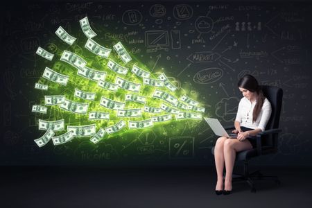 Businesswoman sitting in chair holding laptop with dollar bills coming out concept on background