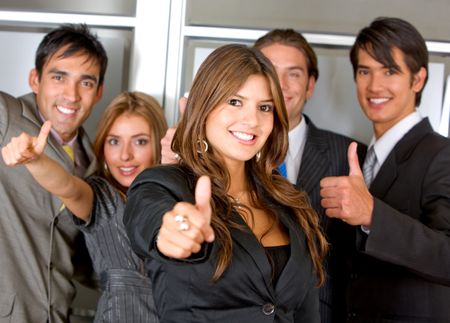 Business group standing in an office with thumbs up