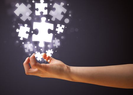 Woman holding shining puzzle pieces in her hand