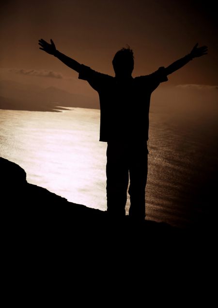 man in front of a cliff with his arms up expressing freedom and happiness