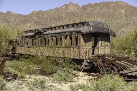 Dilapidated old railroad car deteriorating near rocky mountain in southern Arizona desert