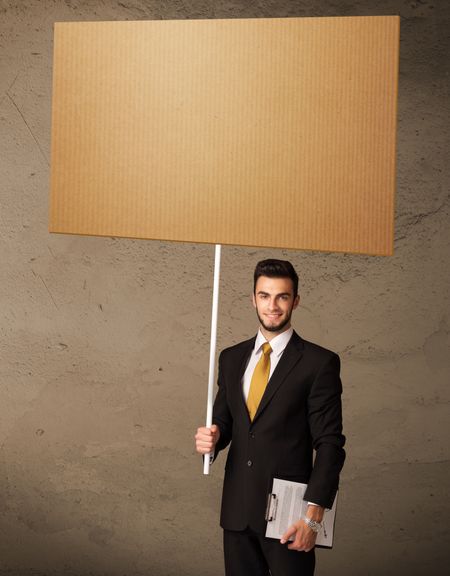 Young businessman holding a blank brown cardboard
